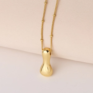 Detailaufnahme eines polierten goldenen Tropfenanhängers an einer Perlenkette mit Hochglanz