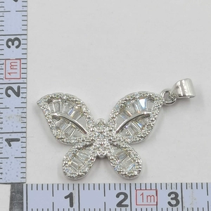Close-up of bow necklace pendant measured with a ruler showing the 2.5cm width detail