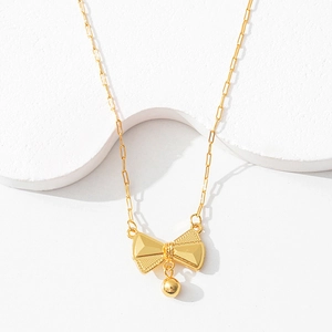 Detailed macro view of a gold bow pendant featuring dot texture and a small gold ball drop