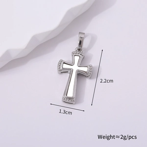 Close-up of vintage silver cross pendant with white inlay and dot relief, 2.2cm x 1.3cm