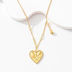 Detailed macro view of the gold heart pendant with floral design and Love engraving