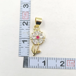 Close-up of gold flower pendant with sparkling zircons and a red center gemstone