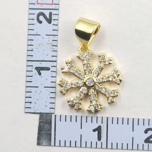 Macro shot of gold snowflake pendant with zircon inlay and measurement scale