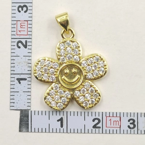 Close-up of gold sunflower pendant with white zircon petals and a smiley face center