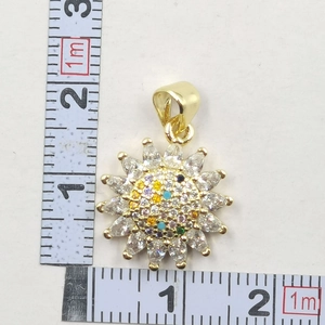 Close-up of golden sunflower clover pendant with zircons showing 20mm size on a ruler