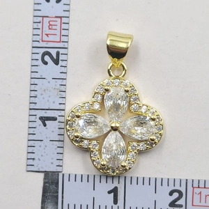 Macro detail of gold four-leaf clover flower pendant with clear zircons and measurement