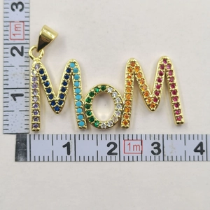 Detailed view of gold MOM letter pendant with rainbow colorful cubic zirconia and measuring tape