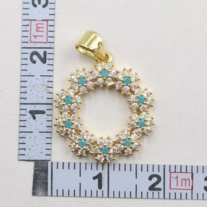 Macro view of gold flower wreath pendant with blue stones and scale measurement