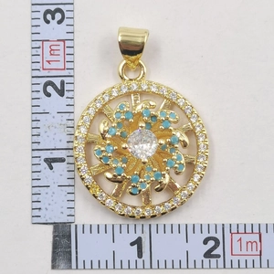 Detailed view of sunflower pendant with blue beads and crystals next to a ruler for scale