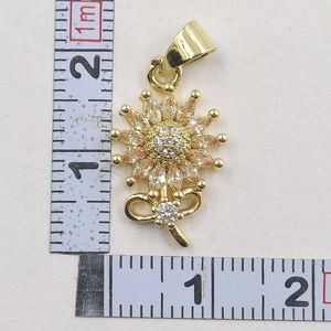 Macro detail of sunflower pendant with champagne cubic zirconia and bow element