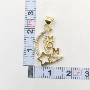 Macro view of gold MOM moon pendant with cubic zirconia and measurement scale detail