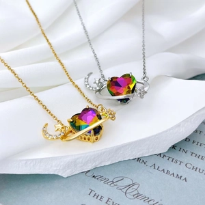 Detailed shot of gold and silver heart pendants with rainbow stones on white silk
