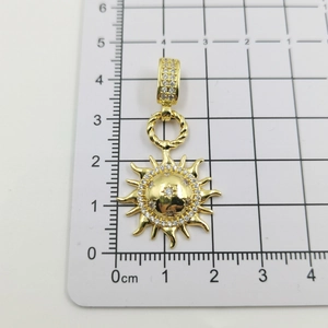 Detailed view of gold sun pendant with white crystals on a grid measurement board