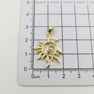 Macro shot of gold sun pendant with crystal center on a centimeter measurement scale