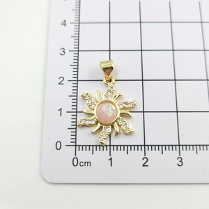 Detailed macro view of gold sunburst pendant with pink opal stone on metric ruler