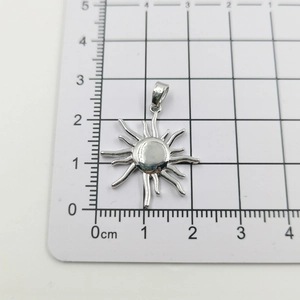 Detail of sunflower pendant with wavy rays on a grid scale to show size measurement