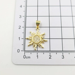 Detail of gold sun flower pendant with sparkling cubic zirconia on a measuring grid