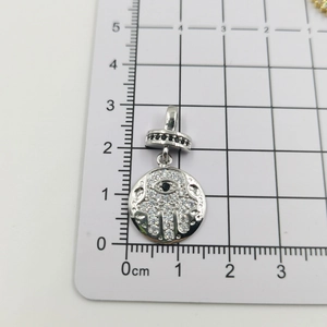 Nahaufnahme von Hamsa Hand Anhänger mit Zirkonia-Steinen auf Maßstab zeigt 1,5cm Durchmesser