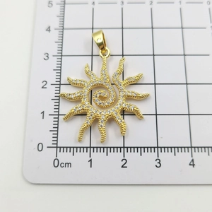 Close-up of gold sun flower pendant with white cubic zirconia on a measuring grid