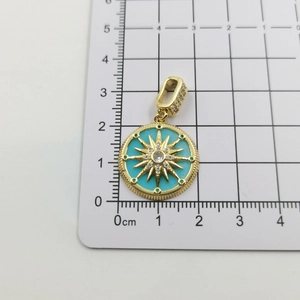 Detail of a 2cm gold pendant with celestial star pattern and blue stone on a scale