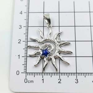Detailed view of silver sun pendant with star inlay over a metric measurement card