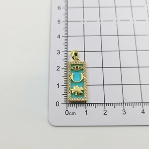Macro view of gold pendant with turquoise enamel and clover charms measured at 2.5cm