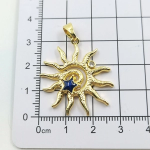 Detail showing gold-plated sun pendant with blue star and zircon on a measuring board