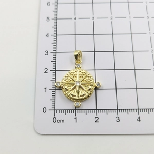 Macro detail of a golden compass sun pendant with white zircons on a measuring scale