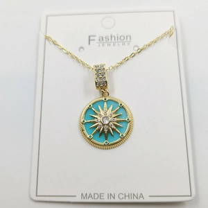 Detailed view of golden necklace featuring a starburst turquoise enamel pendant with crystals