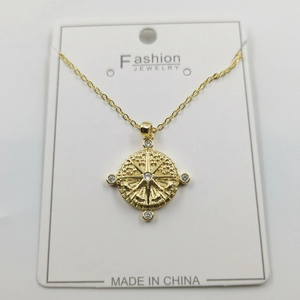Macro shot of gold compass star pendant with small white rhinestones on display card