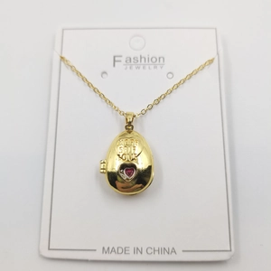 Detail view of golden oval pendant engraved with More Self Love and red heart gemstone