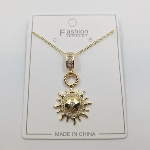 Detailed view of a gold sunburst pendant necklace with cubic zirconia on jewelry card