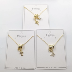 Three-piece gold necklace set with cross, butterfly, and star pendants on white cards