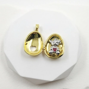 Golden egg pendant necklace opening to reveal a silver teddy bear holding a red heart