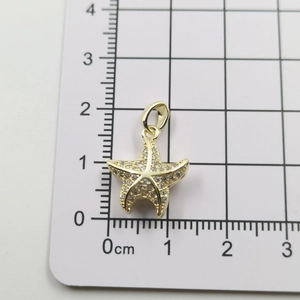 Detailed macro of gold starfish pendant with cubic zirconia inlay on measuring scale