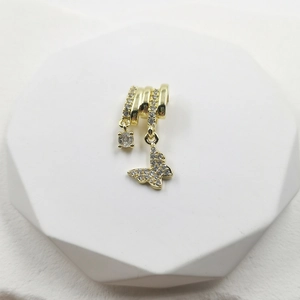 Golden necklace with butterfly and crystal cross pendant on a white geometric stand