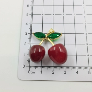 Macro shot of cherry pendant with red beads and green crystals on scale ruler