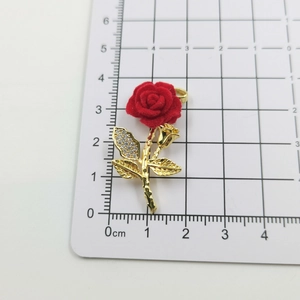 Detailed view of red velvet rose pendant with gold leaves and cubic zirconia accents