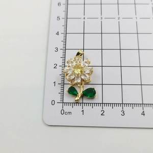 Macro detail of a flower pendant with yellow center and green leaves on a scale