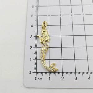 Macro detail of 18k gold plated mermaid pendant with white cubic zirconia and size scale