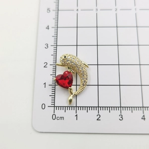 Macro shot of 18k gold plated dolphin pendant with red heart stone and zircon on scale