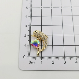 Macro detail of a gold dolphin pendant with micro-set zircon and rainbow heart crystal