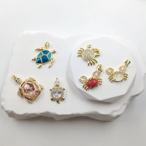 Detailed macro view of gold-plated sea turtle and crab charms with colorful gemstones