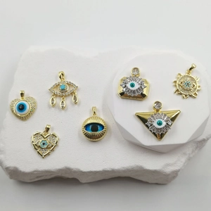 Detail view of 18K gold plated evil eye charms with blue zircon inlay on white marble