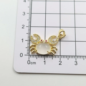 Detailed scale view showing a gold crab pendant with white stone and zircon accents