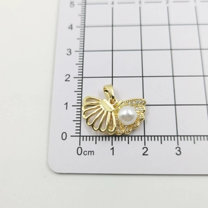 Detailed measurement of shell pendant with pearl and cubic zirconia on ruler card