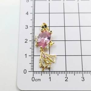 Close-up of golden fish pendant with pink pear-shaped gemstone and cubic zirconia