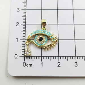 Macro shot of gold plated evil eye pendant with blue zircon stones on scale board