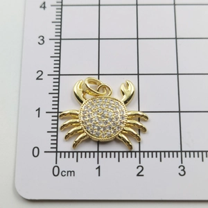 Close-up of golden crab pendant with white crystals on a measuring board showing size