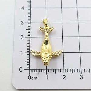 Macro shot of gold whale pendant with zircon stones on a measuring ruler background